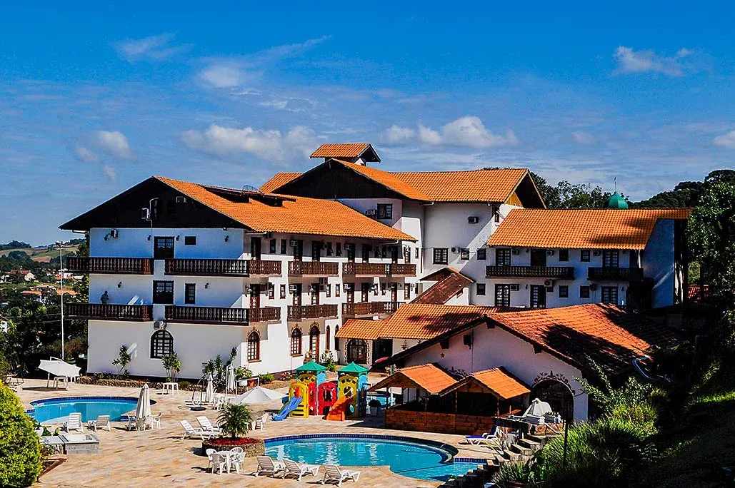 O Treze Tílias Park Hotel visto do alto: prédios brancos com telhados laranja em estilo tirolês, piscinas e jardins