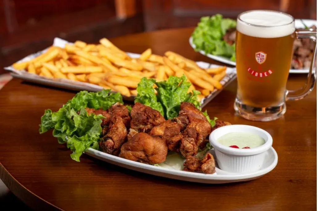 Frango frito com batatas e salada, ao lado de uma caneca de chope LindenBier